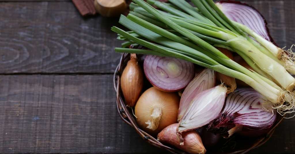 various onions in basket on table